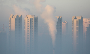 FILE PHOTO - A chimney is seen in front of residential buildings during a polluted day in Harbin, Heilongjiang Province, China, January 21, 2016. REUTERS/Stringer/File Photo