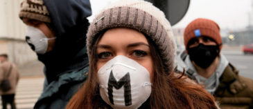 image of a woman wearing a pollution mask with a large "M" painted on it.